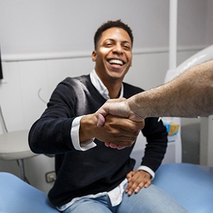 Man smiling while shaking dentist's hand