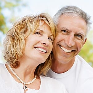 Smiling man and woman outdoors after metal free dental restoration