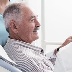 Smiling senior man in dental chair for pocket irrigation