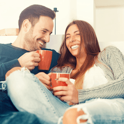 Couple drinking coffee on sofa after porcelain veneer treatment